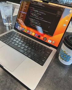 an open laptop computer sitting on top of a table next to a cup of coffee