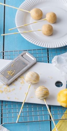 some lemons and garlic on a white plate with skewers next to them