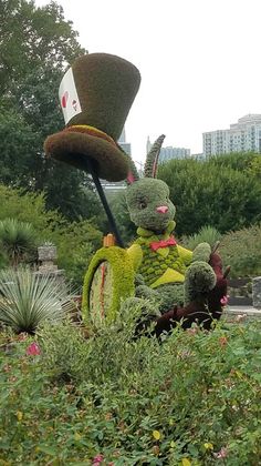 a couple of stuffed animals sitting on top of a lush green field next to bushes