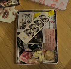 an open suitcase filled with pictures and other items on top of a wooden table next to postcards