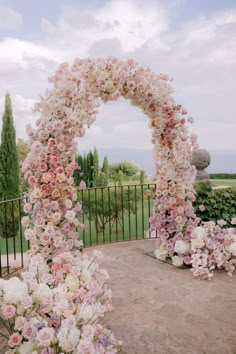 an outdoor wedding ceremony with flowers and greenery on the fenced in lawn area