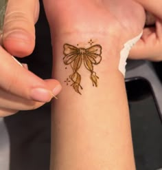 a woman is getting her tattoo done on her left arm and the other hand has a gold bow