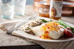 a white plate topped with fish next to rice and veggies on a table