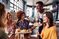 group of friends having lunch together at a restaurant, smiling and looking at each other