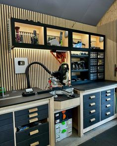 a workbench with lots of drawers and tools on it in front of a striped wall