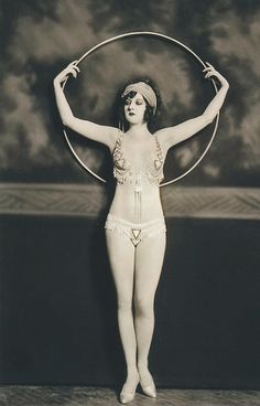 an old photo of a woman with a hoop around her neck and hands in the air