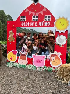 a group of people standing in front of a red barn with farm animals on it