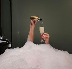 a woman is in the bathtub drinking champagne