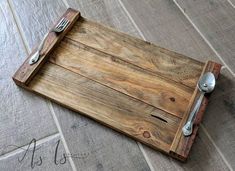 a wooden tray with two forks and spoons sitting on the floor next to a tile floor