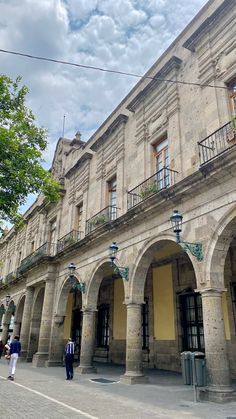 an old building with arches and balconies on the front, along with people walking by