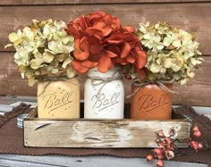 three mason jars with flowers in them sitting on a wooden tray next to a burlick