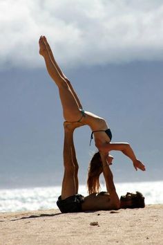 a woman doing a handstand on the beach