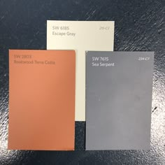 three different shades of gray, white and orange are on the table next to each other