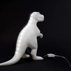 a white dinosaur lamp sitting on top of a black table next to a charger