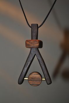 a wooden object hanging from a black cord