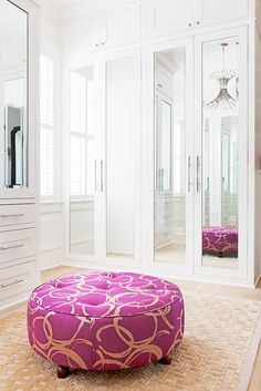 a pink ottoman sitting on top of a rug in front of a white closet door