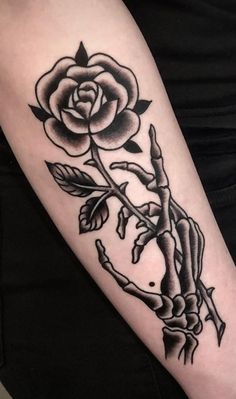 a black and white rose tattoo on the left arm, with an arrow in the middle