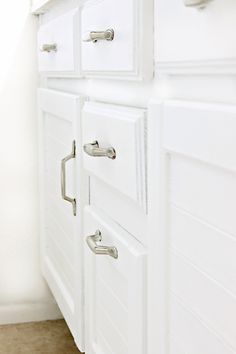 a white cabinet with handles and drawers in a room