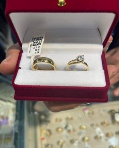 two gold wedding rings in a red velvet box with white and yellow diamond accents on them