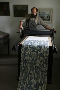 a man is typing on an old typewriter in front of some pictures and paintings