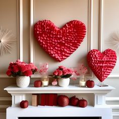 two heart shaped paper decorations on a mantel with candles and vases filled with flowers