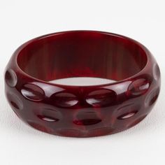 This is part of Chairish’s Costume Jewelry assortment.  This is a stunning crimson-red marble Bakelite bracelet bangle. It features a chunky domed shape with geometric and deeply carved designs. The color is an intense red marble tone with cloudy swirling.  Measurements: Inside across is 2.50 in diameter (6.3 cm) - outside across is 3 in diameter (7.7 cm) - width is 1.07 in (2.7 cm) - The inner circumference of the bracelet is 7.79 in (19.78 cm).  Please see the measurements noted above in the d Luxury Red Bangle, Elegant Red Round Cuff Bracelet, Elegant Bakelite Bangle As Gift, Elegant Bakelite Bangle As A Gift, Modern Red Bangle Bracelet, Modern Red Bangle Bracelets, Elegant Bakelite Bracelets As A Gift, Elegant Bakelite Bracelets For Gift, Bakelite Bracelets