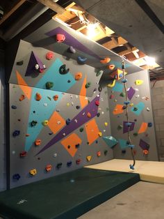 an indoor climbing wall with colorful rocks and climbing ropes hanging from it's sides