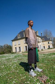 a man standing on top of a lush green field next to a tall building with windows