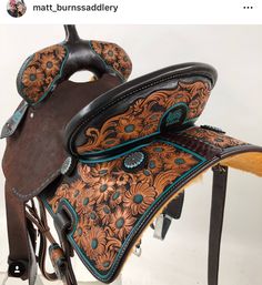 a brown and blue horse saddle sitting on top of a wooden stand