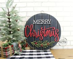 a merry christmas sign sitting on top of a wooden table next to a small tree