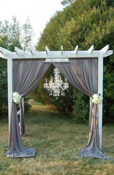 an outdoor wedding ceremony set up with chandelier and draping on the grass