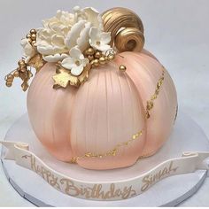 there is a pink pumpkin cake with flowers on it's head and gold trimmings