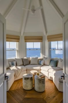 a living room filled with lots of furniture next to the ocean on top of a wooden floor