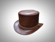 Discover unparalleled style with our El Dorado Top Hat, a true masterpiece from Voodoo Hatter. Crafted from genuine cowhide leather, this hat embodies luxury and craftsmanship. The Unbanded design and perfect fit from Size 6 to Size 8 make it a versatile choice for those who appreciate quality and style. This top hat isn't just an accessory; it's a statement. Whether you're a fan of steampunk fashion, a biker seeking the perfect hat, or simply a man looking for a classic and stylish headwear option, our El Dorado Top Hat caters to every taste. Voodoo Hatter's expertise shines in every detail. The leather top hat provides essential sun protection while exuding timeless elegance. Its adaptability makes it the ideal choice for various occasions, from casual outings to formal events. Indulge i Brown Leather Top Hat With Short Brim, Luxury Brown Classic Top Hat, Luxury Brown Leather Top Hat, Vintage Adjustable Leather Top Hat, Steampunk Brown Leather Hat, Leather Top Hat, Brown Leather Top, Mode Steampunk, Top Hats