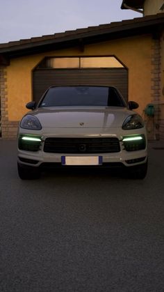 a white sports car parked in front of a house at night with its lights on