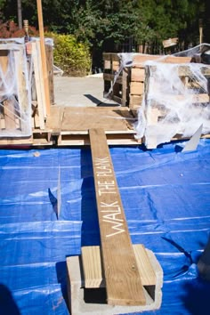 a wooden sign that is on top of a blue tarp