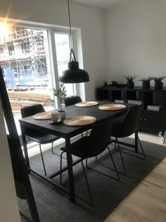 a dining room table with chairs and a vase on it in front of a window