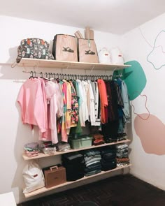 a closet with clothes and bags hanging on the wall next to a shelf filled with purses