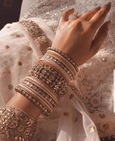 a close up of a person's hands wearing bracelets and rings on their fingers