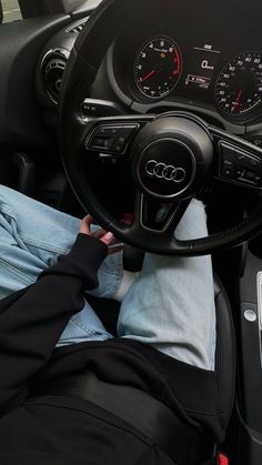 a person sitting in the driver's seat of a car with their feet on the steering wheel