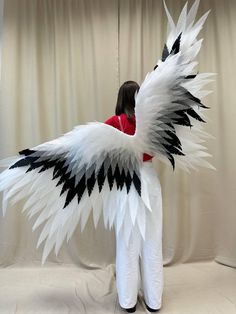 a woman standing in front of a white and black angel wings costume with red shirt