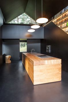 an open kitchen with black walls and wooden counter tops, along with modern lighting fixtures