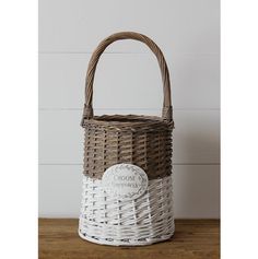 a white and brown basket sitting on top of a wooden table next to a wall