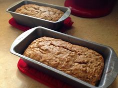 two loafs of bread sitting in pans on a table