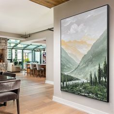 a painting hanging on the wall in a living room next to a dining room table