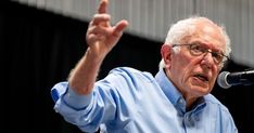 an older man giving a speech with his hand in the air and holding a microphone