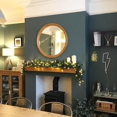 a living room filled with furniture and a fire place covered in christmas lights next to a mirror