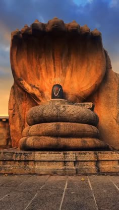 a large stone sculpture with a clock on it's face in front of a cloudy sky