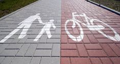 the bike path is painted on brick and has white arrows pointing in opposite directions to each other