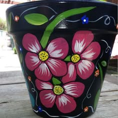 a painted flower pot sitting on top of a wooden table